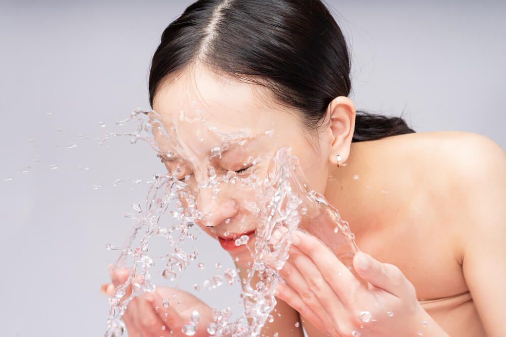 beautiful asian woman washes her face with pure water